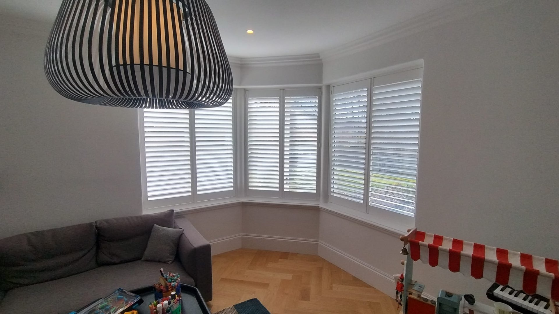 Large bay window in a lounge fitted with white plantation shutters