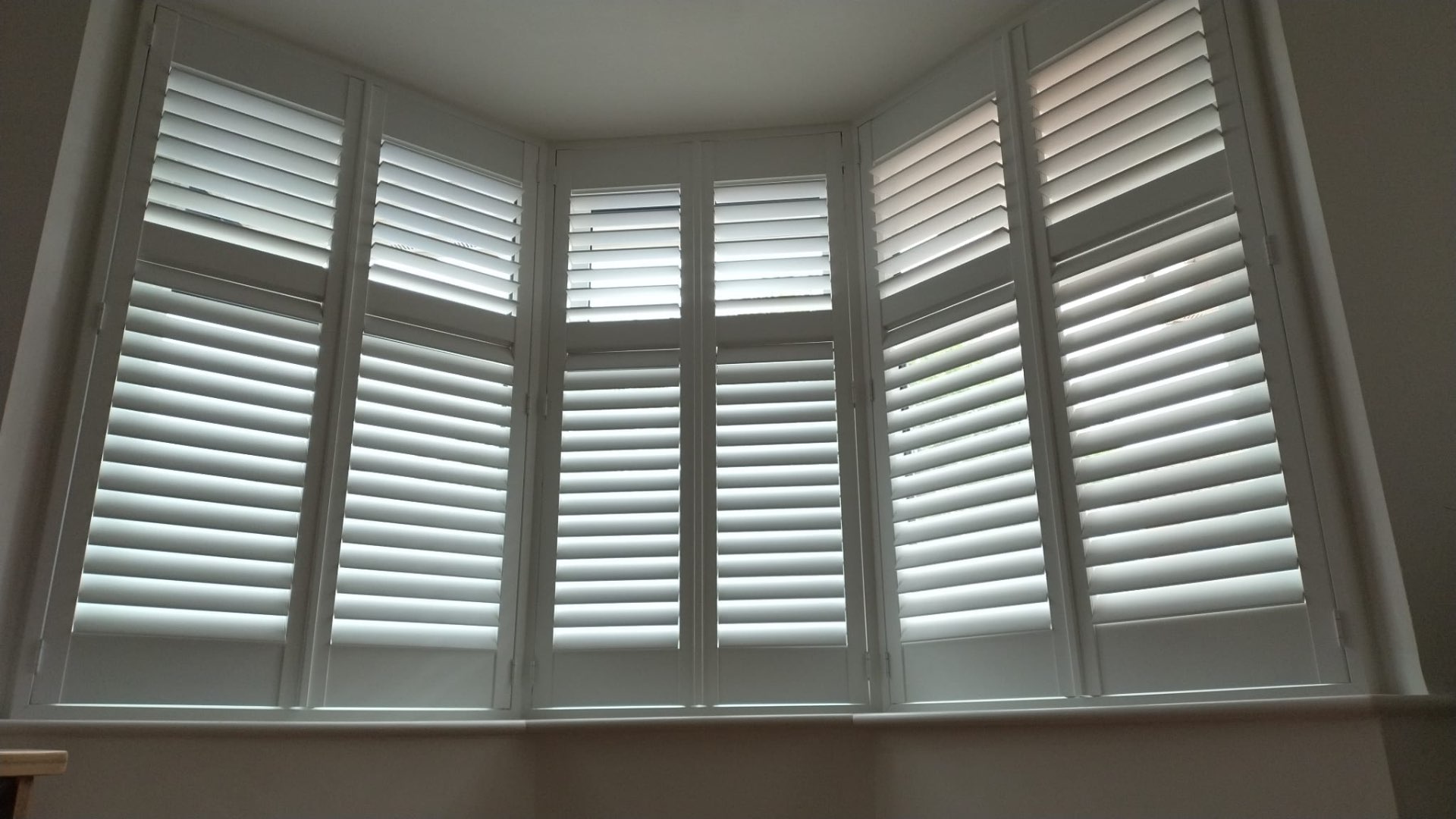 Angled bay window with full-height shutters
