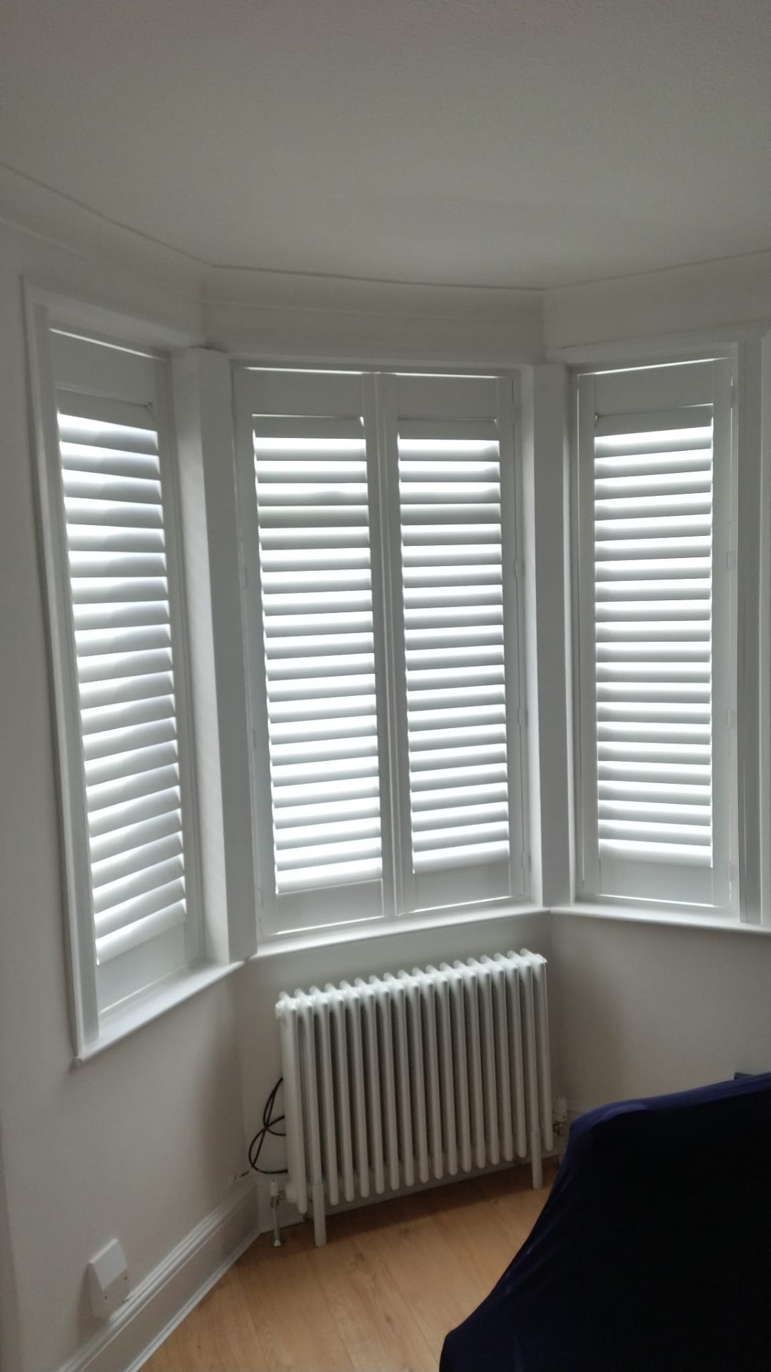 Bay bedroom dressed in full-height white shutters